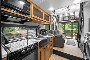 Cocina compacta con estufa, microondas y armarios de madera.