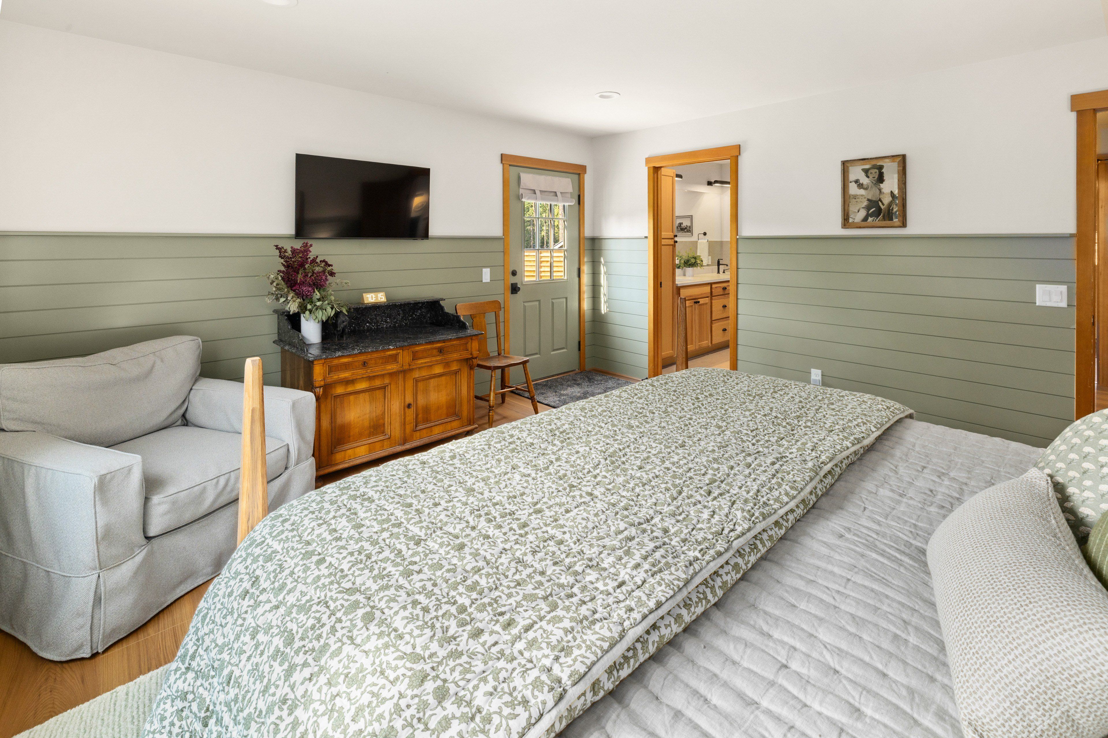 Une chambre à coucher avec un lit, un bureau, une chaise et un téléviseur fixé au mur.