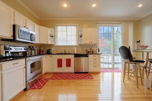 Una cocina moderna con armarios blancos, electrodomésticos de acero inoxidable y un comedor con mesa y sillas.