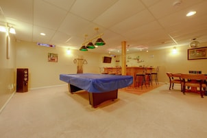 Una habitación con mesa de billar, zona de bar y mesa de comedor con sillas.