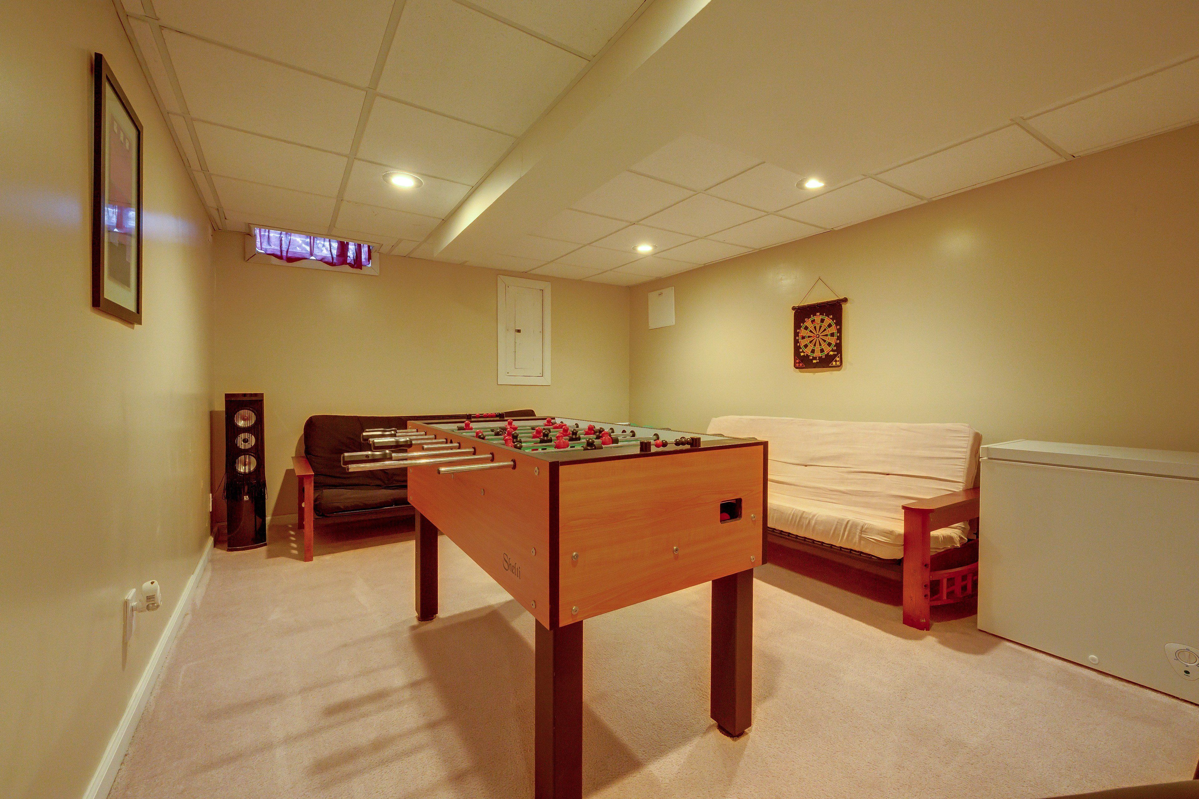 A room with a foosball table, a sofa, and a bed.