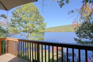 A wooden deck with a view of a lake and trees.