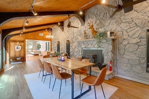 A dining area with a stone wall, a fireplace, and a wooden ceiling.