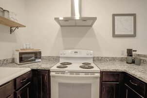 Una cocina con estufa blanca, microondas, gabinetes de madera oscura y encimera de granito.