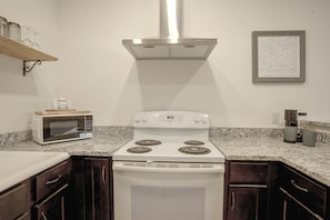 A kitchen with a white stove, a microwave, dark wooden cabinets, and a granite countertop. - Rapidan Trading Post : Historic Charm (Rapidan)