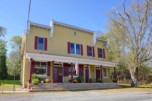 Um edifício amarelo de dois andares com persianas vermelhas e varanda.