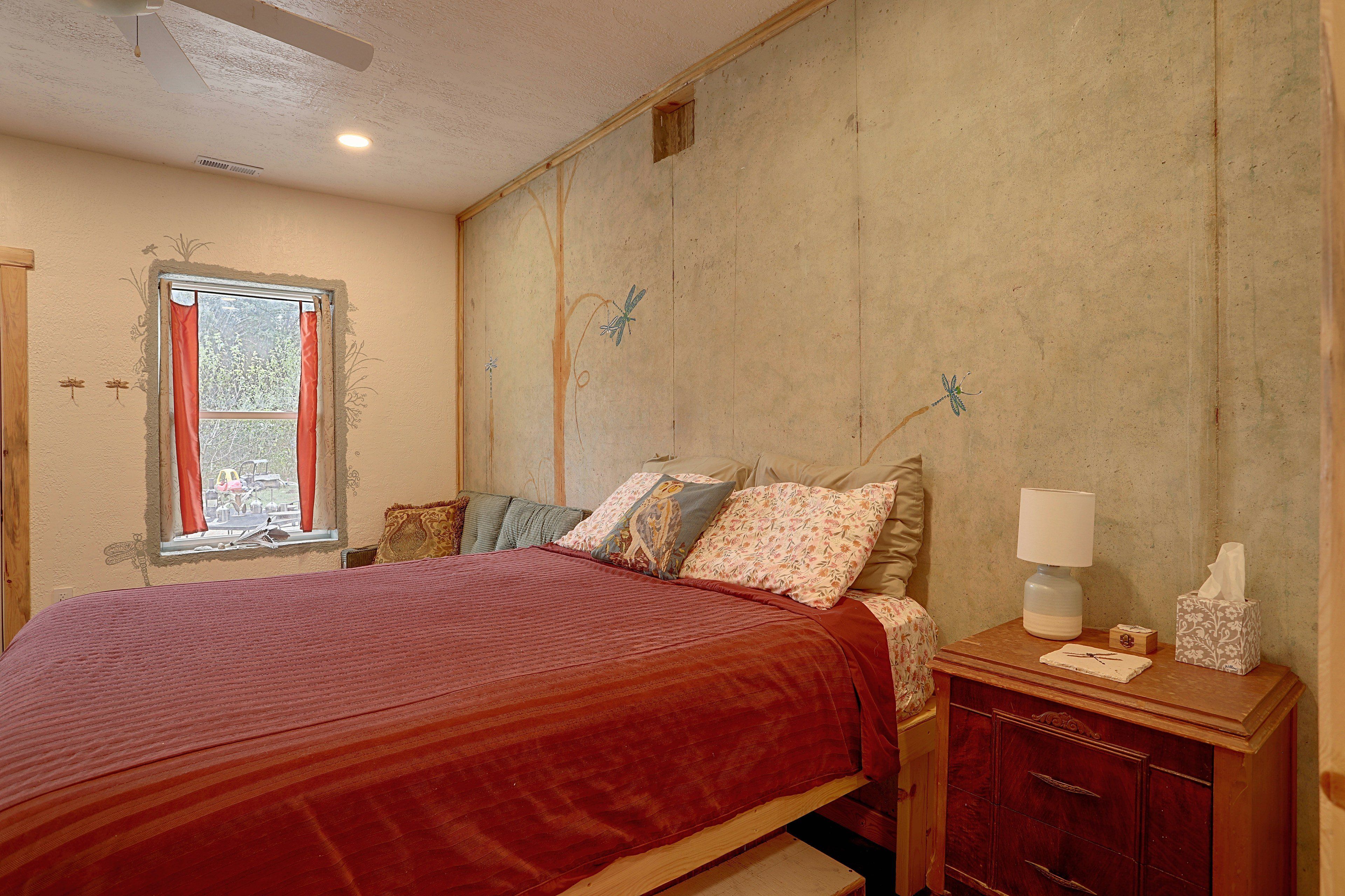 Un dormitorio con una cama, una mesita de noche, una lámpara y una ventana con cortinas.