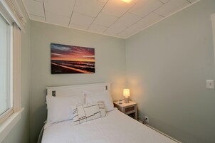 Un dormitorio con cama, una mesita de noche con lámpara y un cuadro en la pared.