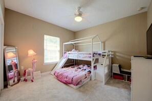 A child's bedroom with bunk beds, a desk, a mirror, and a ceiling fan.