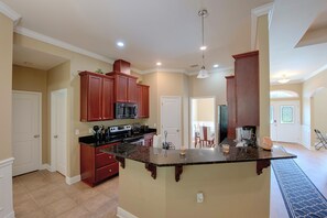 A spacious kitchen with a central island, wooden cabinets, and modern appliances.