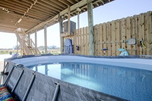 A swimming pool with a wooden deck and a covered area.