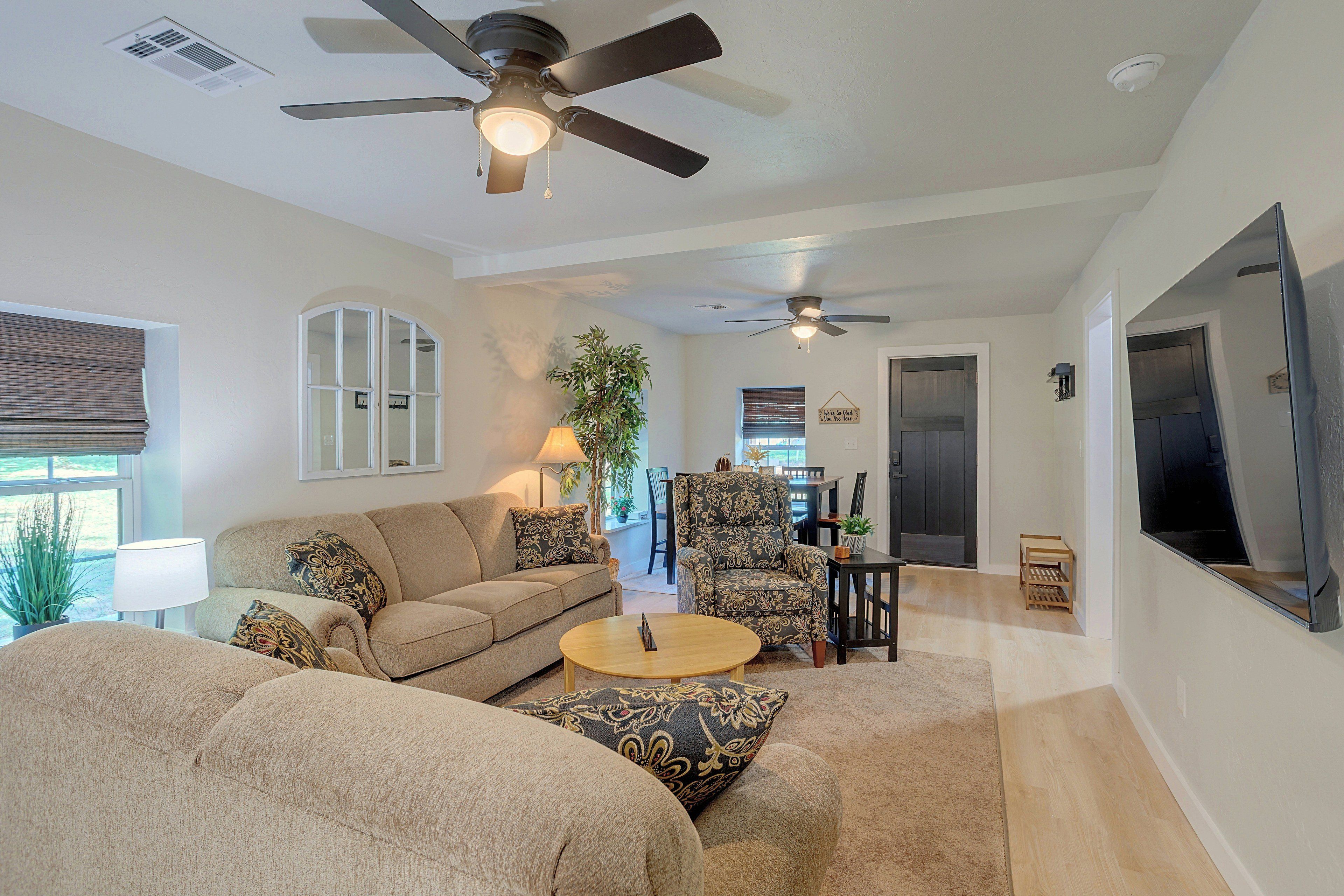 A spacious living room with a ceiling fan, a sofa, a coffee table, and a television.