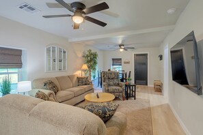 A spacious living room with a ceiling fan, a sofa, a coffee table, and a television. - Guthrie Home in the Heart of Historic Downtown! (Guthrie)