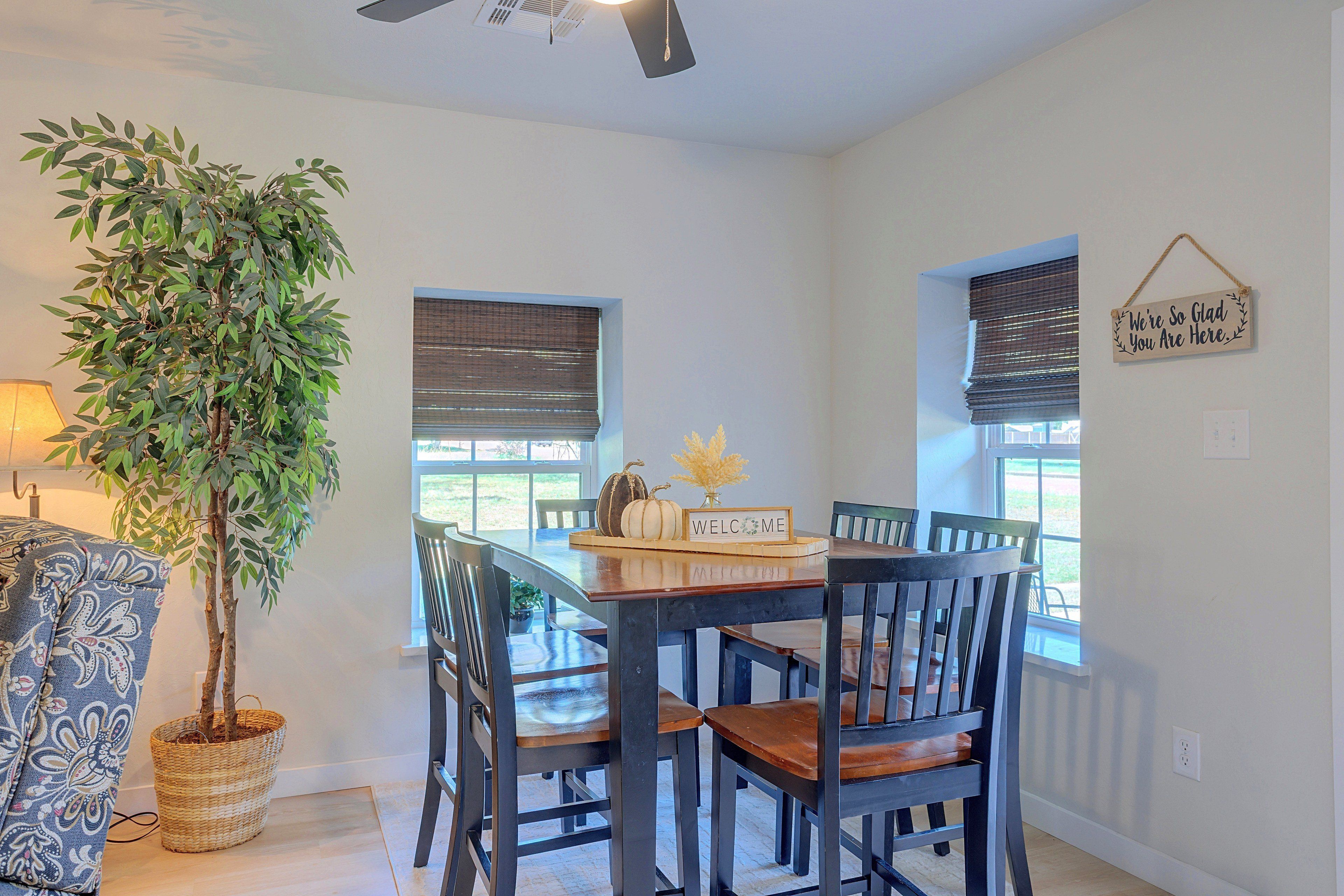 A dining area with a table, chairs, a potted plant, and a welcome sign.