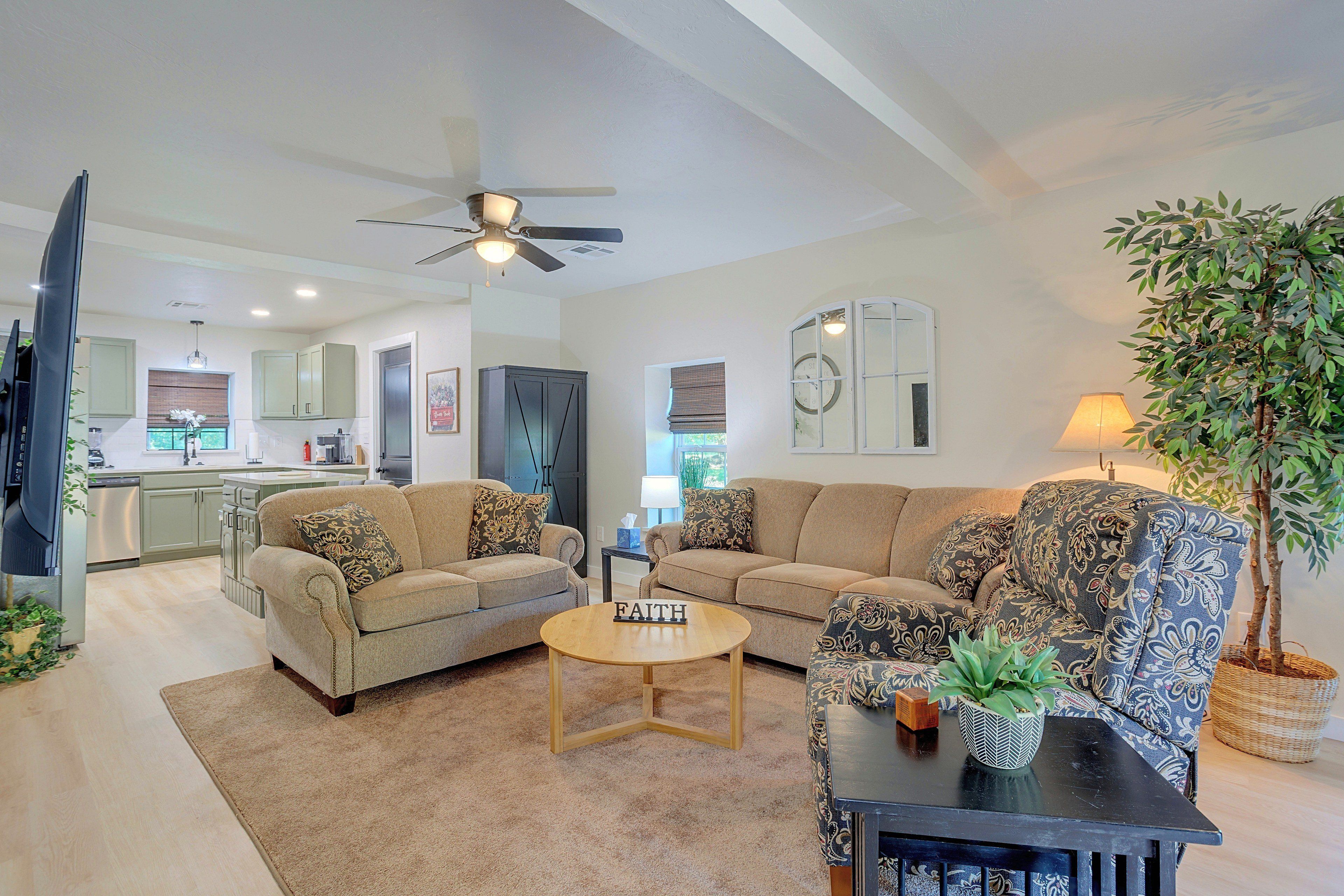 A living room with a sofa, armchairs, a coffee table, and a television.