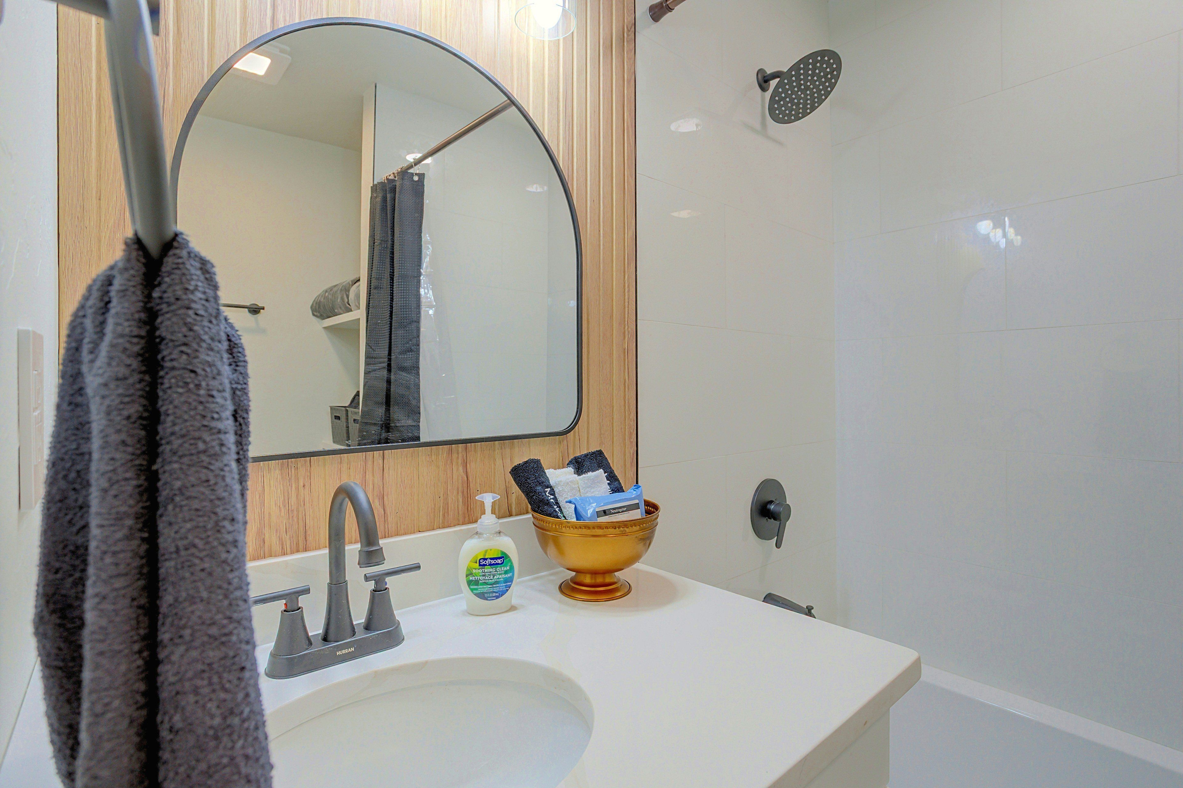 Un baño con lavabo, espejo y ducha.