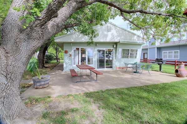 A small, single-story building with a patio area featuring a table and benches.