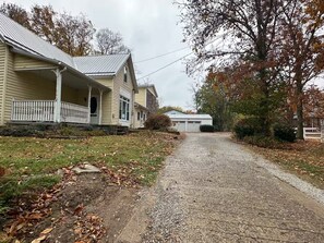 Ein gepflegter Schotterweg führt zu einem zweigeschossigen Haus mit Veranda und Garage.