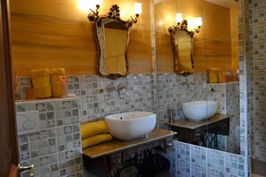 Een badkamer met twee wasbakken, een spiegel en een plank met handdoeken.