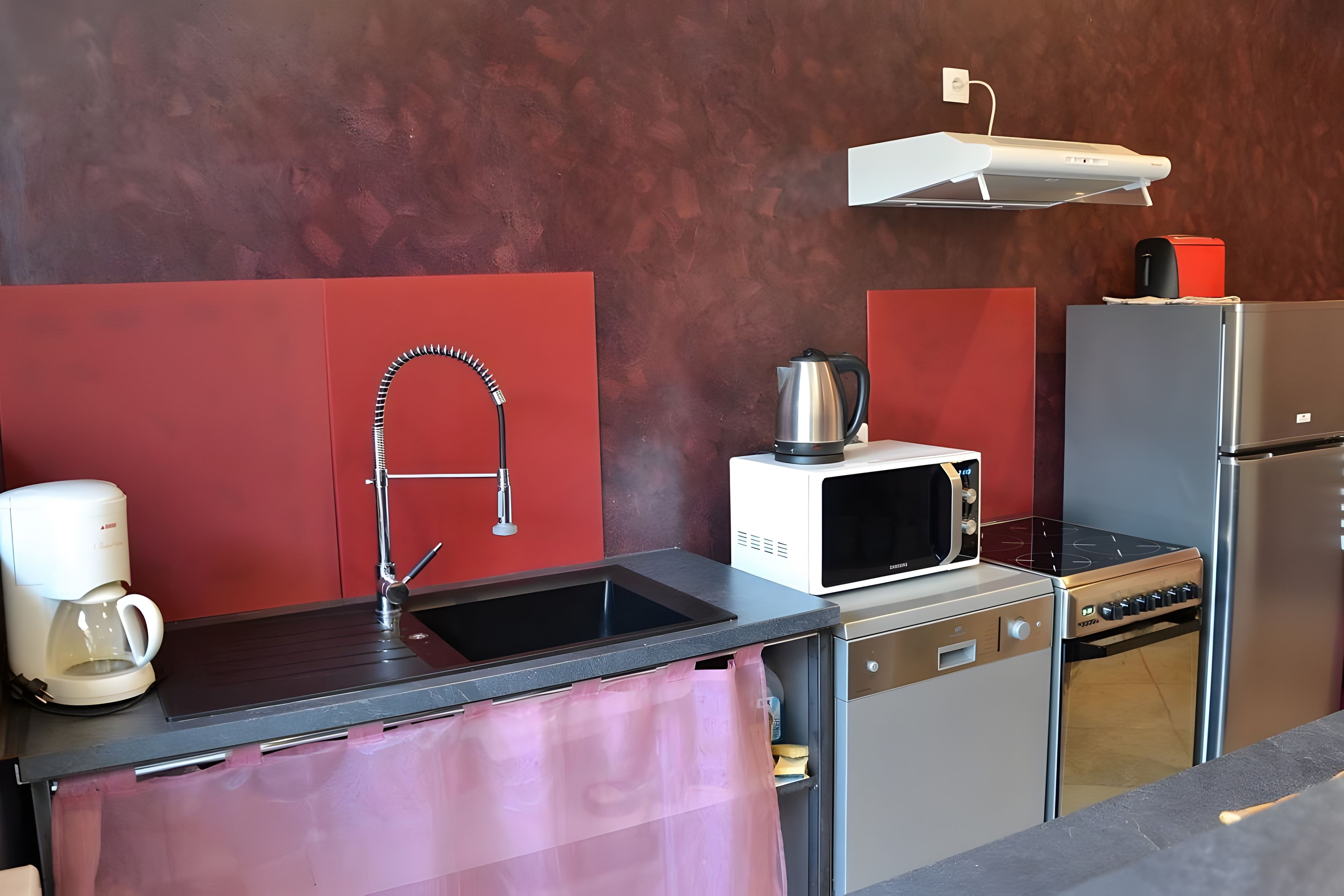A compact kitchenette with a sink, a coffee maker, a microwave, a kettle, and a refrigerator.