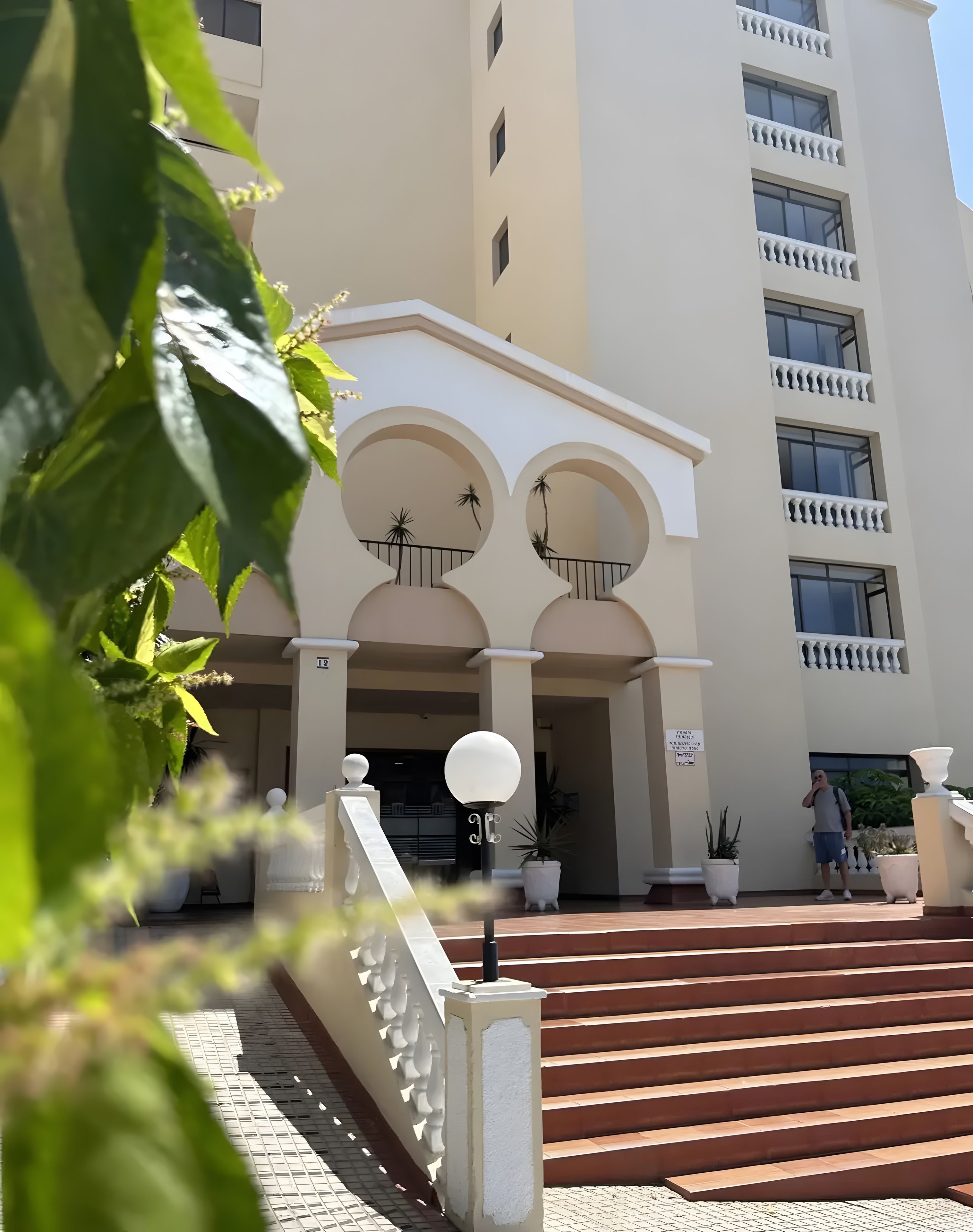 Un edificio con una entrada imponente, varios balcones y una escalera que conduce a la entrada.