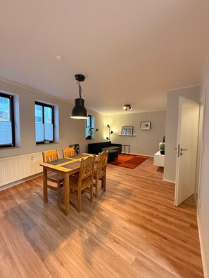 Un amplio salón con mesa de comedor, sillas, un sofá negro y chimenea.