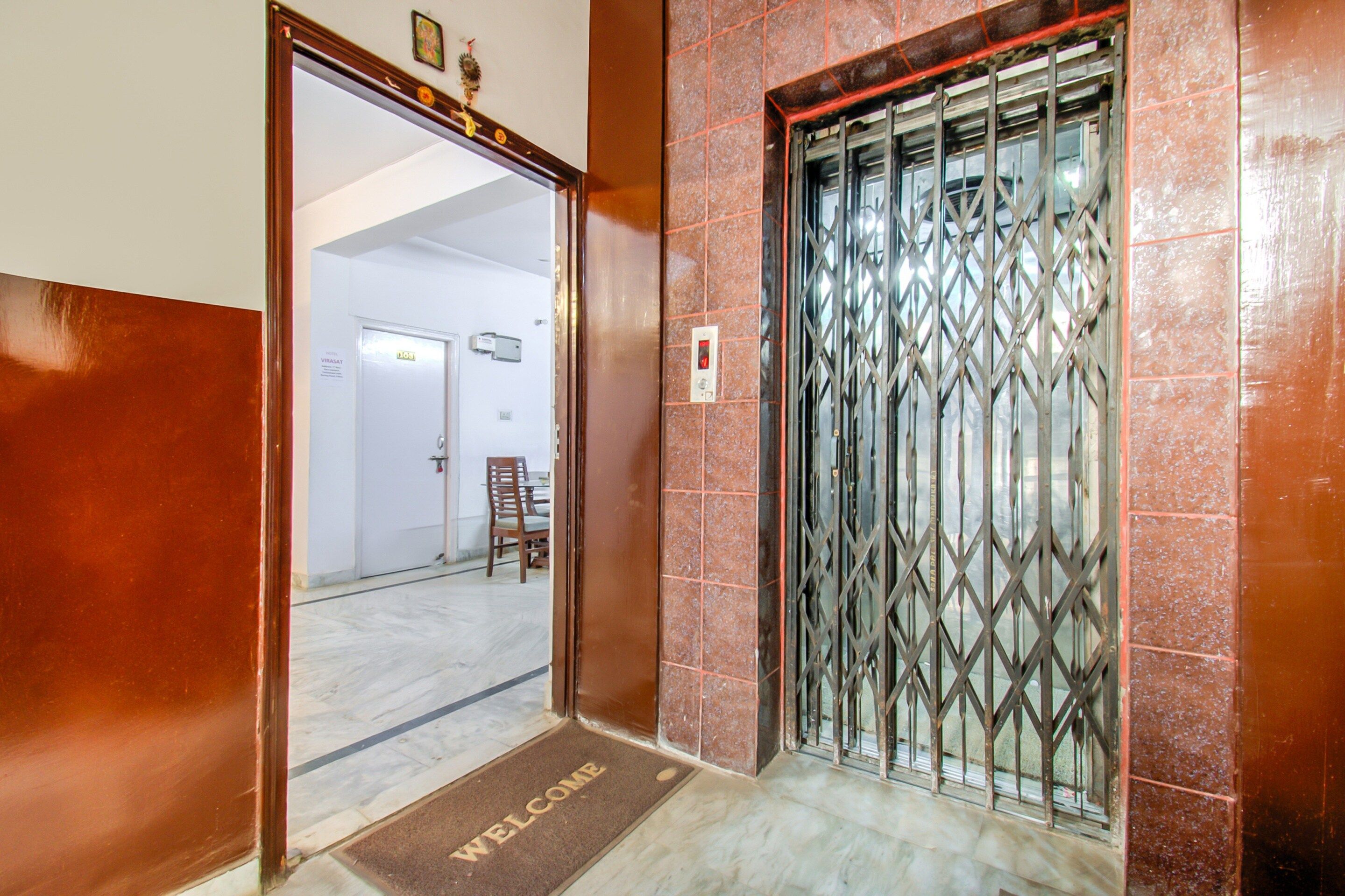 A hotel entrance with a metal gate, a welcome mat, and a door with a sign indicating room number 103.