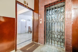 Entrada de hotel con una reja metálica, felpudo y una puerta con el número de habitación 103 indicado.