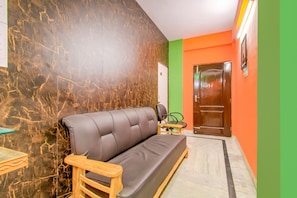 Una habitación con un sofá, una silla de madera, una mesita y una puerta.
