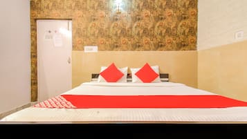 A hotel room with a bed, a door, and a wall with a patterned wallpaper.