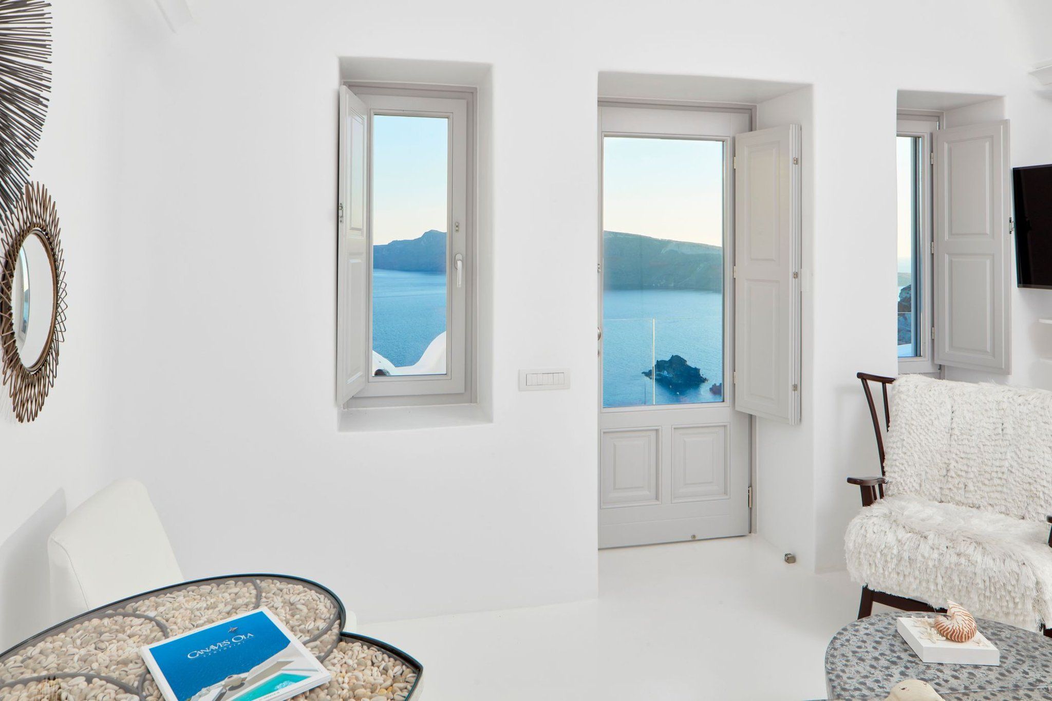 Un salon moderne offrant une vue sur une mer calme et des montagnes lointaines.