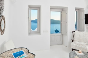 Un salon moderne offrant une vue sur une mer calme et des montagnes lointaines.