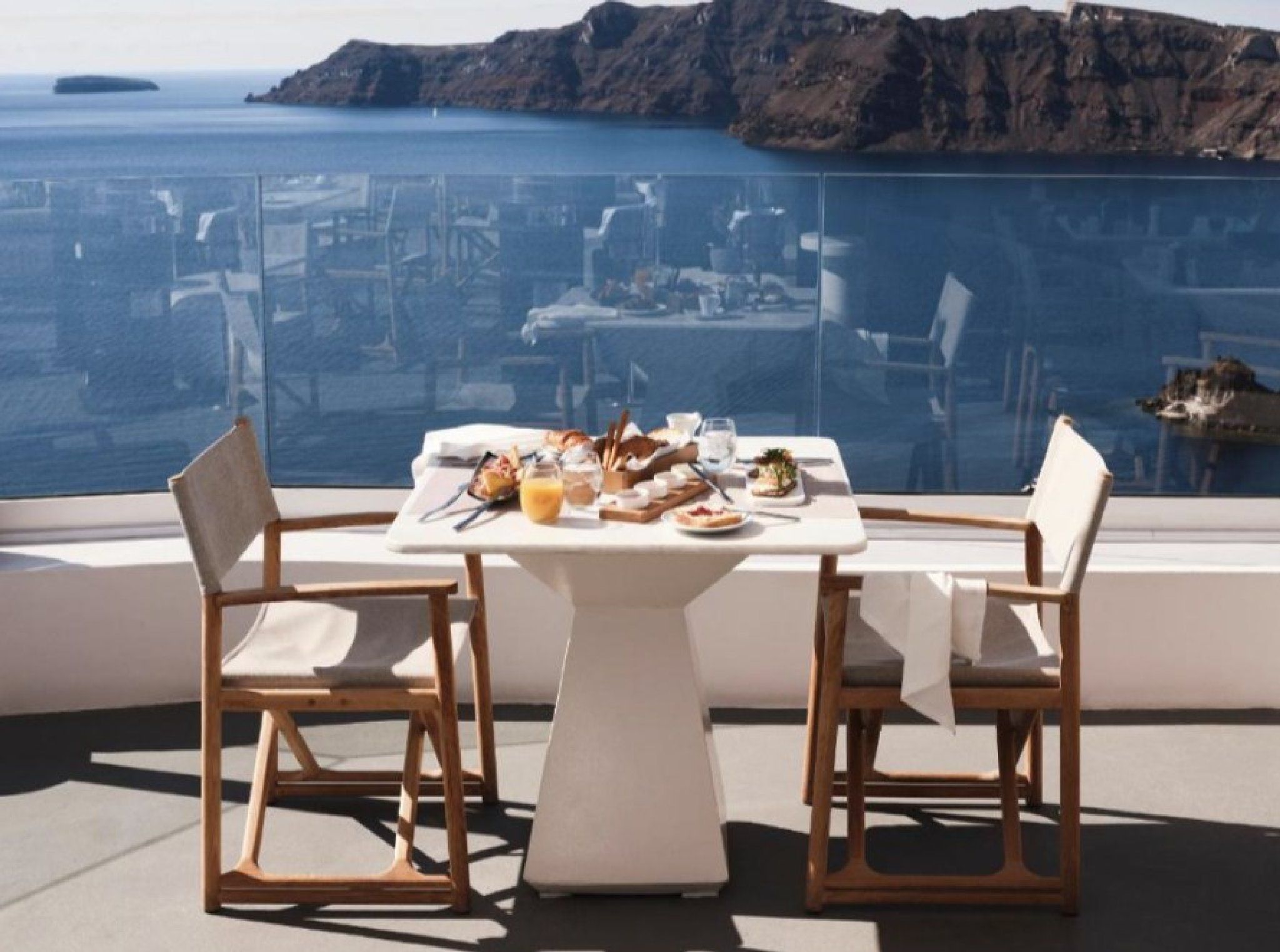 Une table dressée pour deux personnes, avec vue sur la mer et un paysage montagneux.