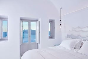 Une pièce blanche avec un lit, une fenêtre et une vue sur la mer.