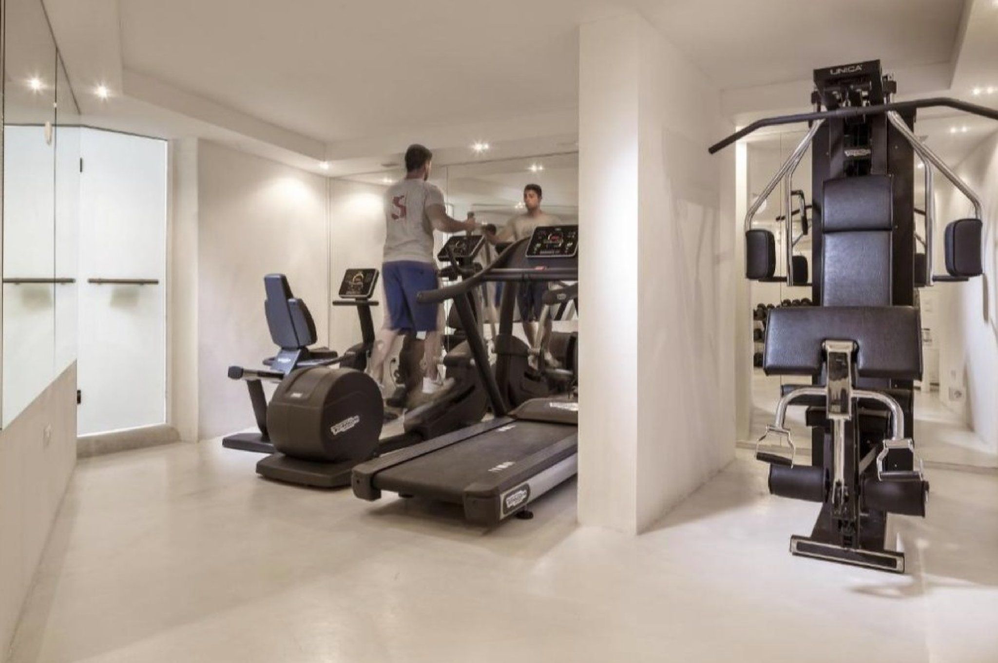 Une salle de sport moderne équipée de tapis de course, d’un appareil elliptique et de machines de musculation.