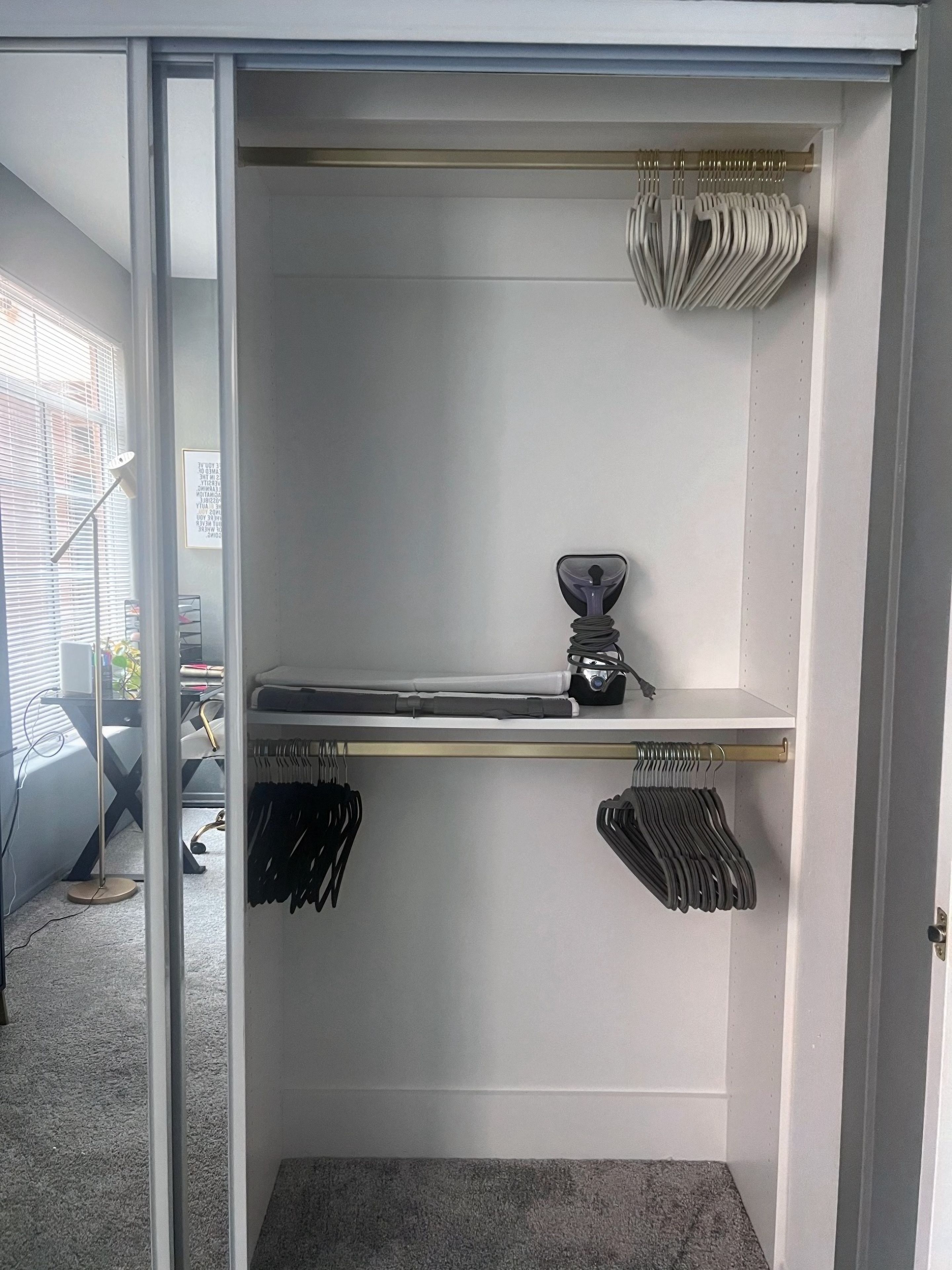 Un vestidor con un zapatero, una barra para colgar ropa y un estante con una aspiradora.
