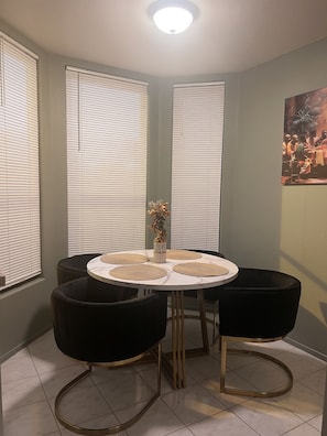 A dining area with a round table, black chairs, and a vase with dried flowers. - Luxury Designer Tulum-African Craftsman Get-Away (Oceanside)
