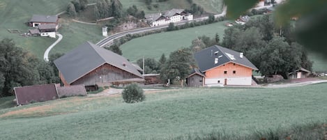 A rural landscape with a winding road, a barn, and a house with a sloped roof.