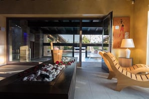 A modern interior with a pool, a wooden lounge chair, and a decorative arrangement of stones and flowers. - Colle Indaco Resort (Ortezzano)
