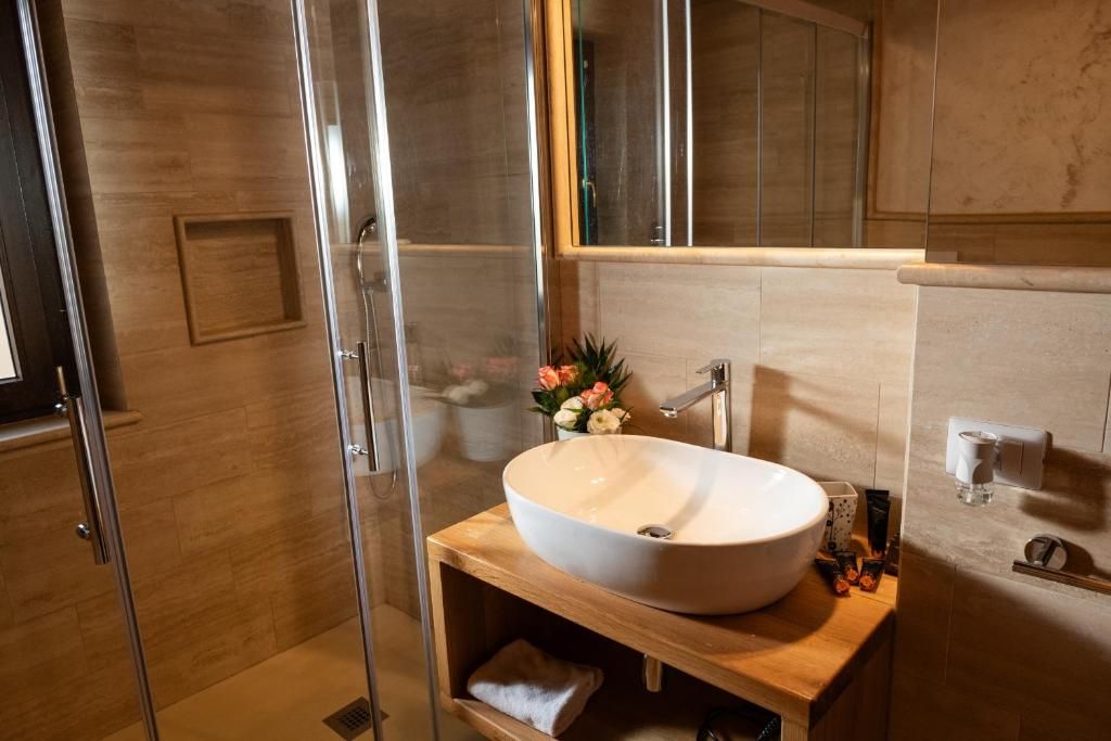 Un baño moderno con cabina de ducha de vidrio, tocador de madera con un lavamanos grande y un espejo encima.