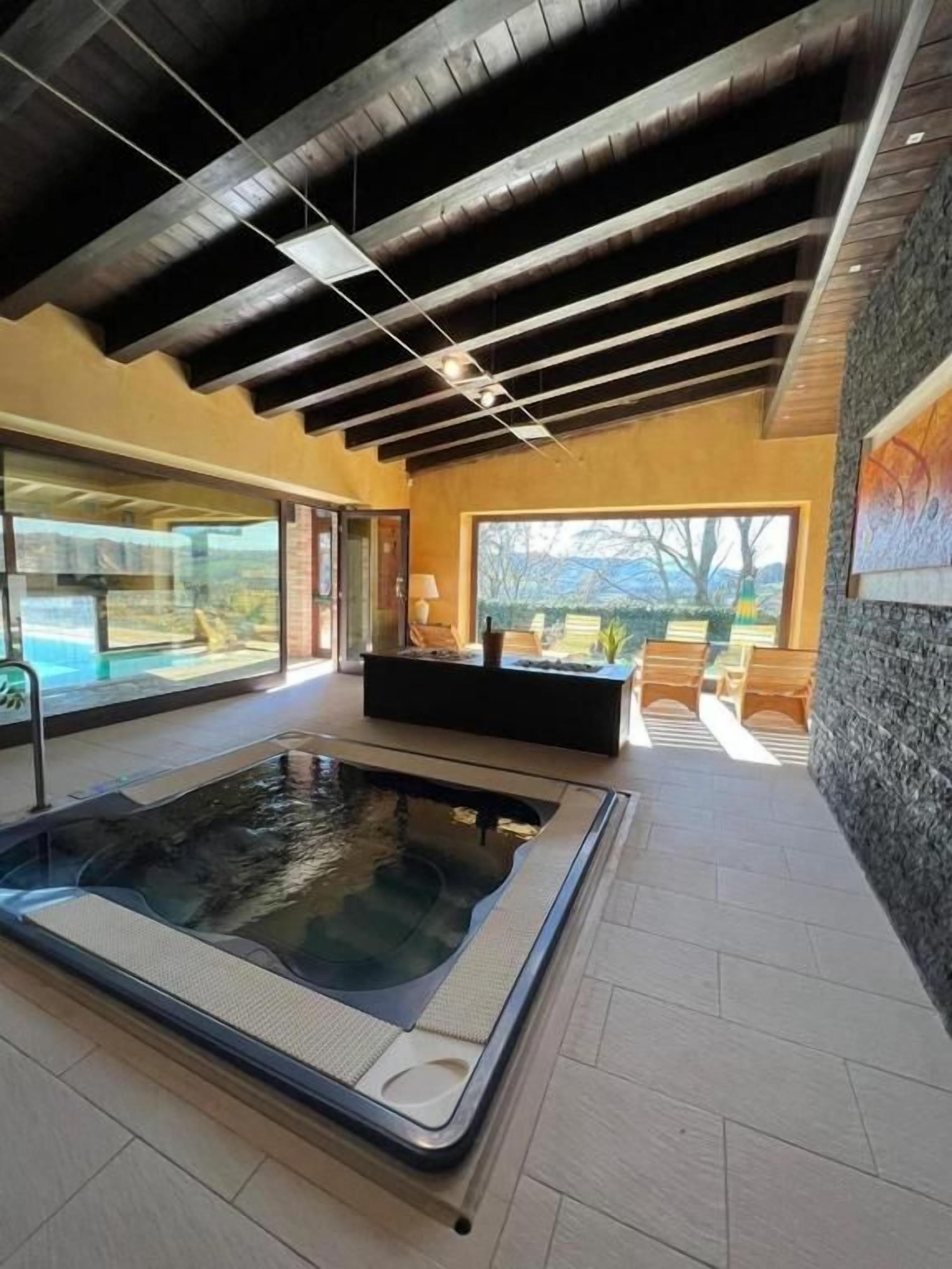 Piscina interior moderna con techo de madera y vistas al exterior.