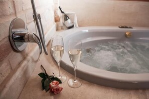 A bathtub with two glasses of champagne, a showerhead, and a rose on the floor. - Colle Indaco Resort (Ortezzano)