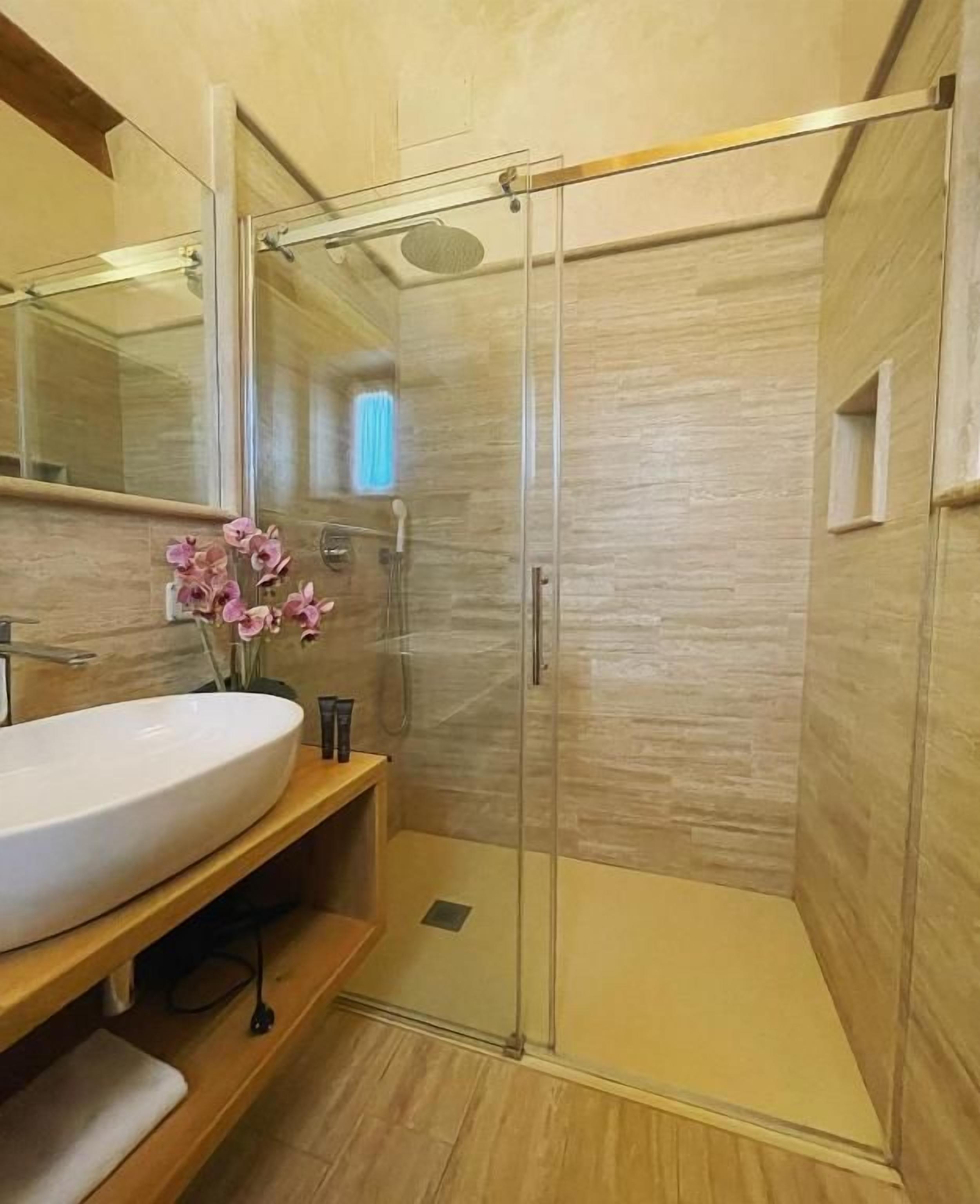 Une salle de bain moderne avec une douche à parois de verre, un lavabo blanc et un meuble-lavabo en bois.