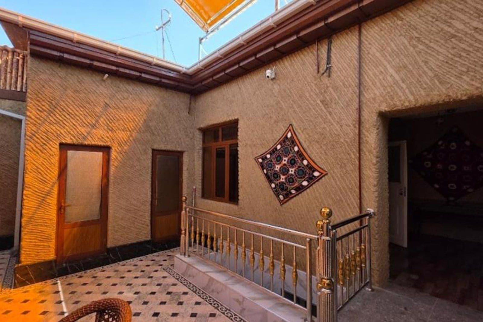 Un patio con piso de baldosas, barandilla de metal y una puerta.