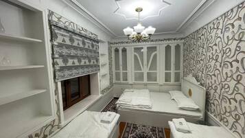 Una habitación con cama, ventana, candelabro y paredes con diseño.