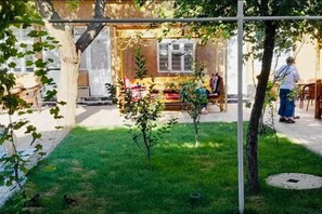 A residential garden with a lawn, a small tree, and a fence. - Guesthouse Anora 4 (Samarkand)