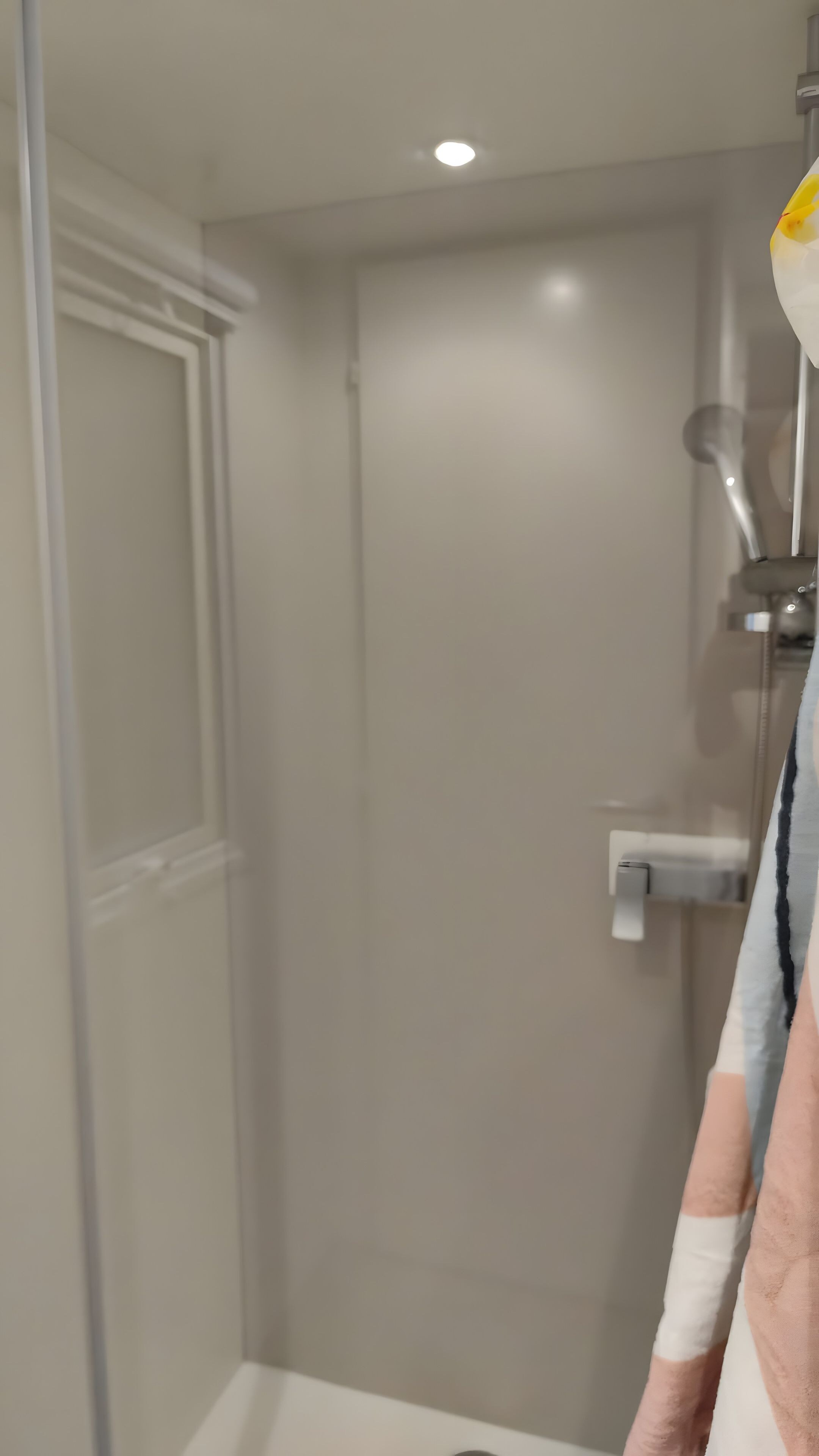A bathroom with a glass shower enclosure, a white sink, and a towel rack.