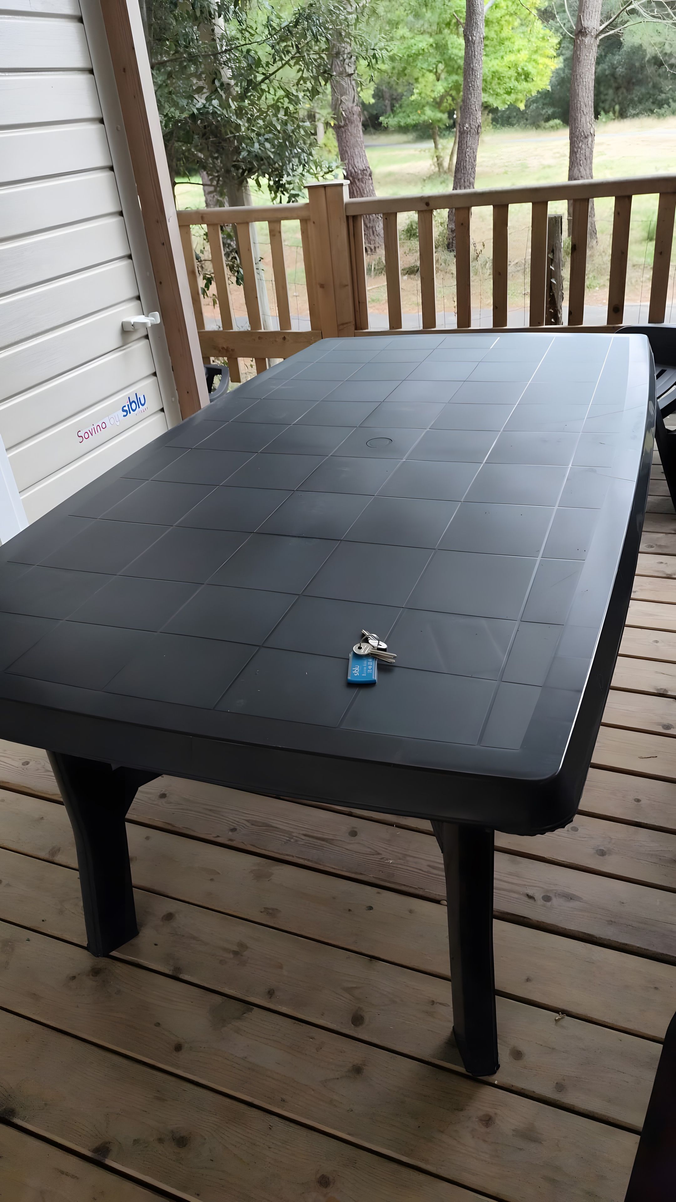 A black table with a keychain on it, placed on a wooden deck.