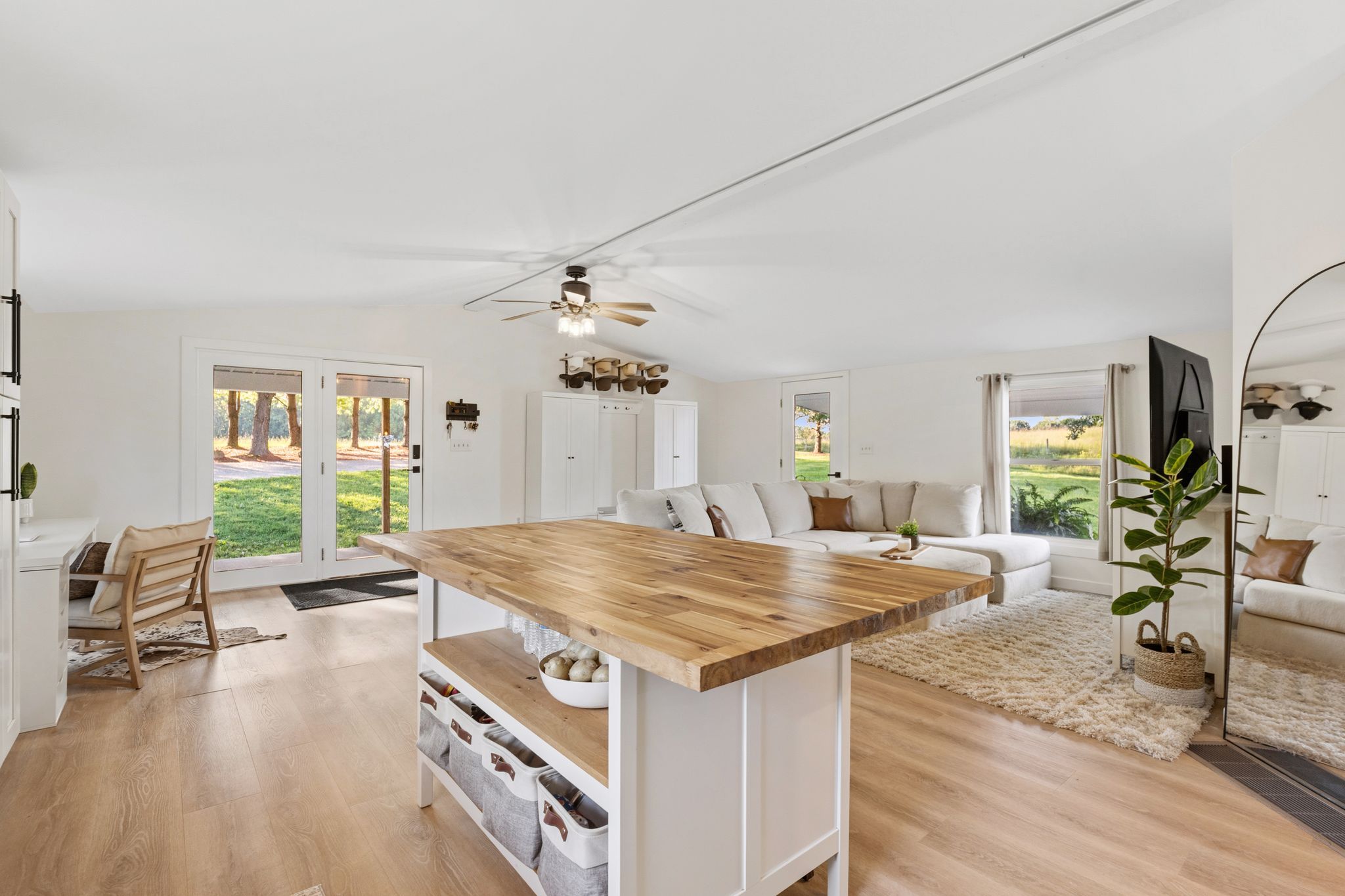 Een ruime woonkamer met een houten eettafel, een bank en een groot raam met uitzicht op de omgeving.