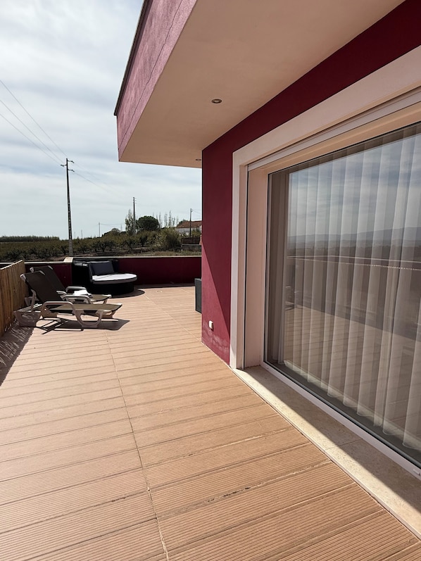 A covered outdoor area with a patio, lounge chairs, and a sliding glass door.